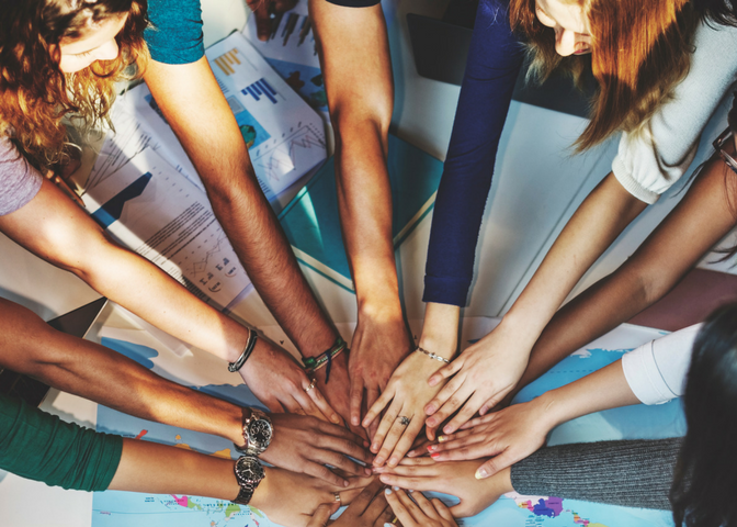 Diverse group of people put their hands together to show collaboration and teamwork
